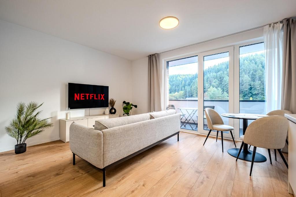a living room with a couch and a tv and a table at Apartmán s výhľadom na Vysoké Tatry a les in Svit