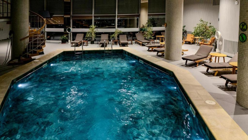a swimming pool in a lobby with chairs and tables at Grand Hotel Bucharest in Bucharest