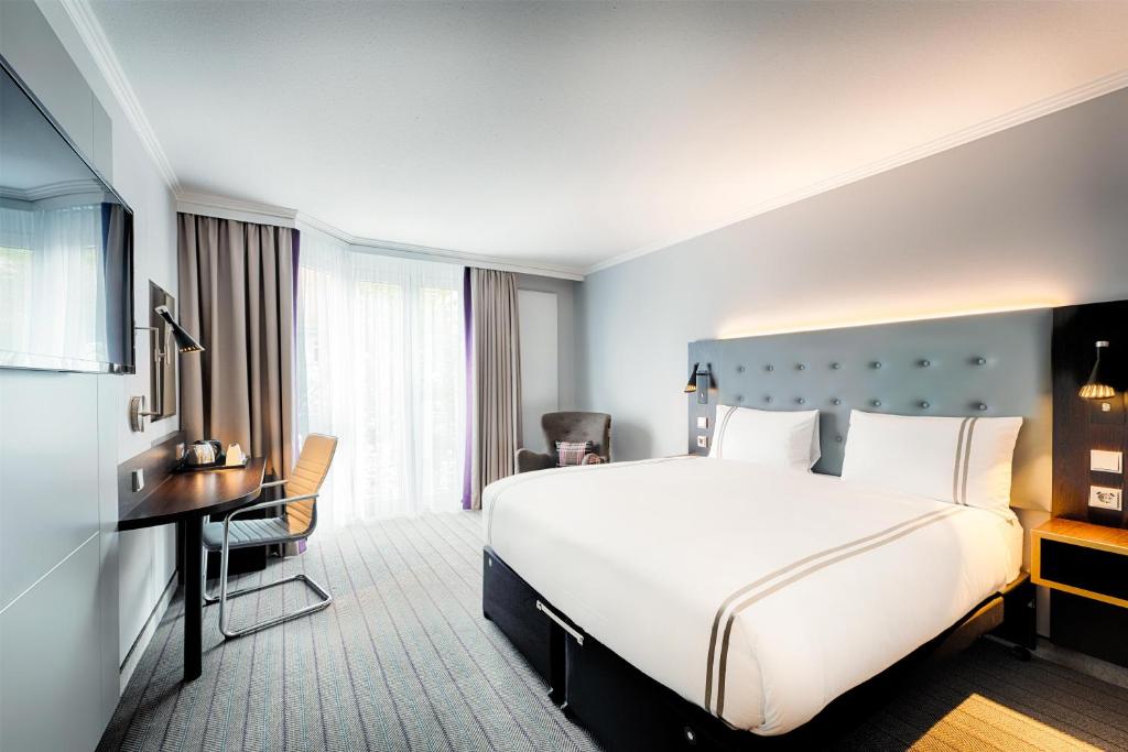 a hotel room with a large white bed and a desk at Premier Inn Stuttgart Bad Cannstatt in Stuttgart