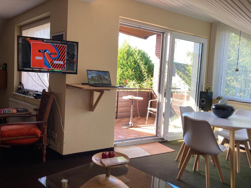 a living room with a television and a table and a door at Helles Apartment mit Balkon in ruhiger Lage in Hameln