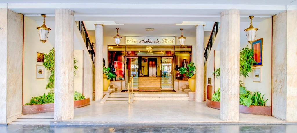 a lobby of a hotel with columns and a staircase at New Ambassador Hotel in Harare