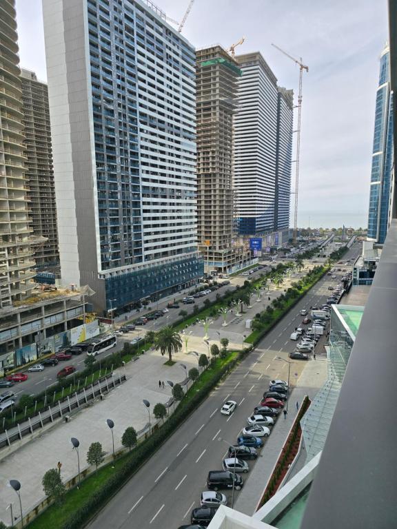 a city street with parked cars and tall buildings at Blue sky in Itʼkhvisi