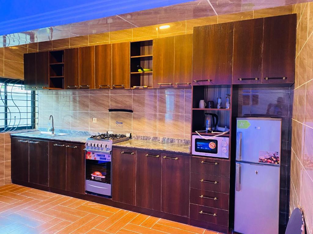 a kitchen with wooden cabinets and a white refrigerator at Seaside Lodging in Limbe
