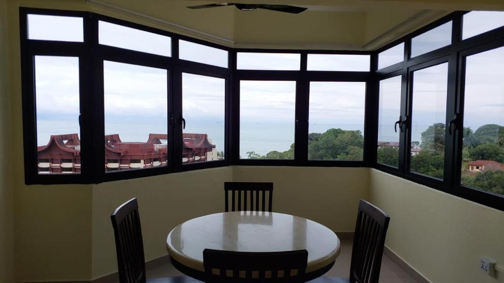 a table and chairs in a room with windows at Batu Ferringhi Luxury Seaview Suite - 3Br in Batu Ferringhi