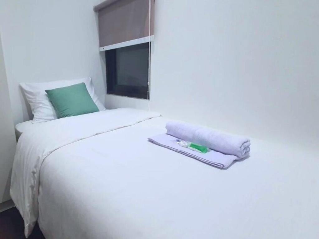 a white bed with a towel on top of it at The Breakout Room ICE BSD in Serpong