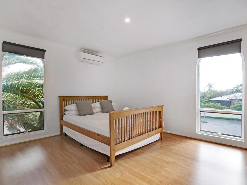 a white bedroom with a bed and two windows at Adelaide Holiday Homes in Adelaide