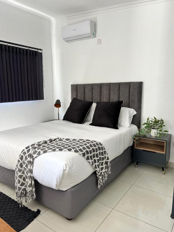 - une chambre avec un grand lit et une tête de lit grise dans l'établissement Cottage in Gaborone West Phase 1, à Gaborone