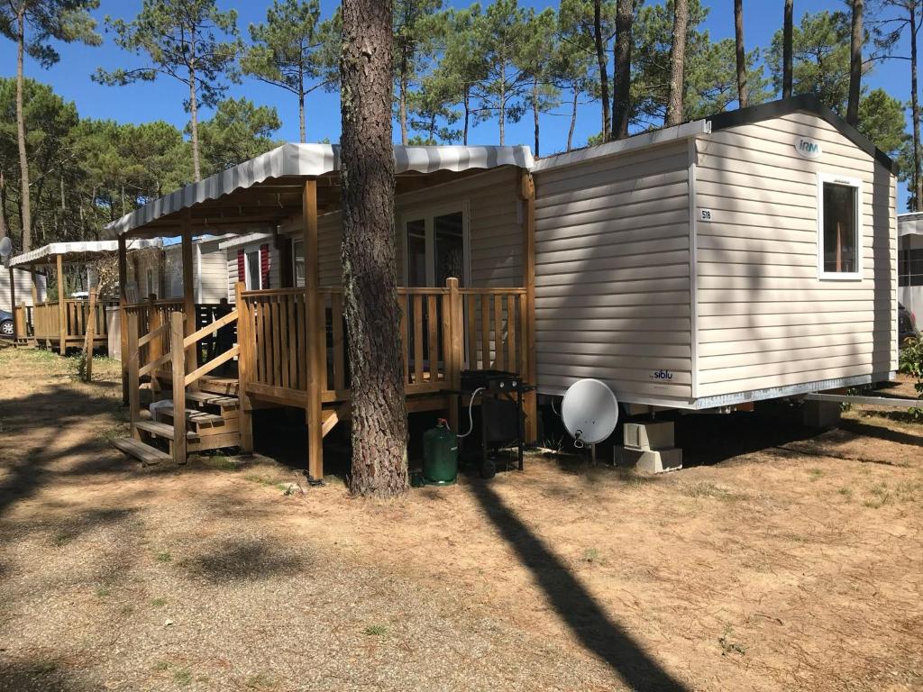 a tiny house with a porch and a tree at MH518 3chambres et 1 sdb de 40m2 dans camping 4 étoiles in Saint-Julien-en-Born