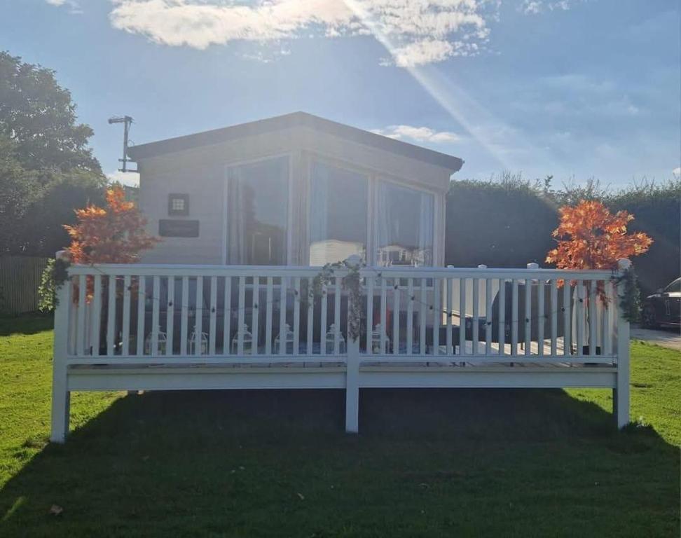 Una gran casa blanca con un porche en el césped en Lovely 8 Berth Caravan With Large Decking At Withernsea Sands Ref 79005Kg, en Waxholme