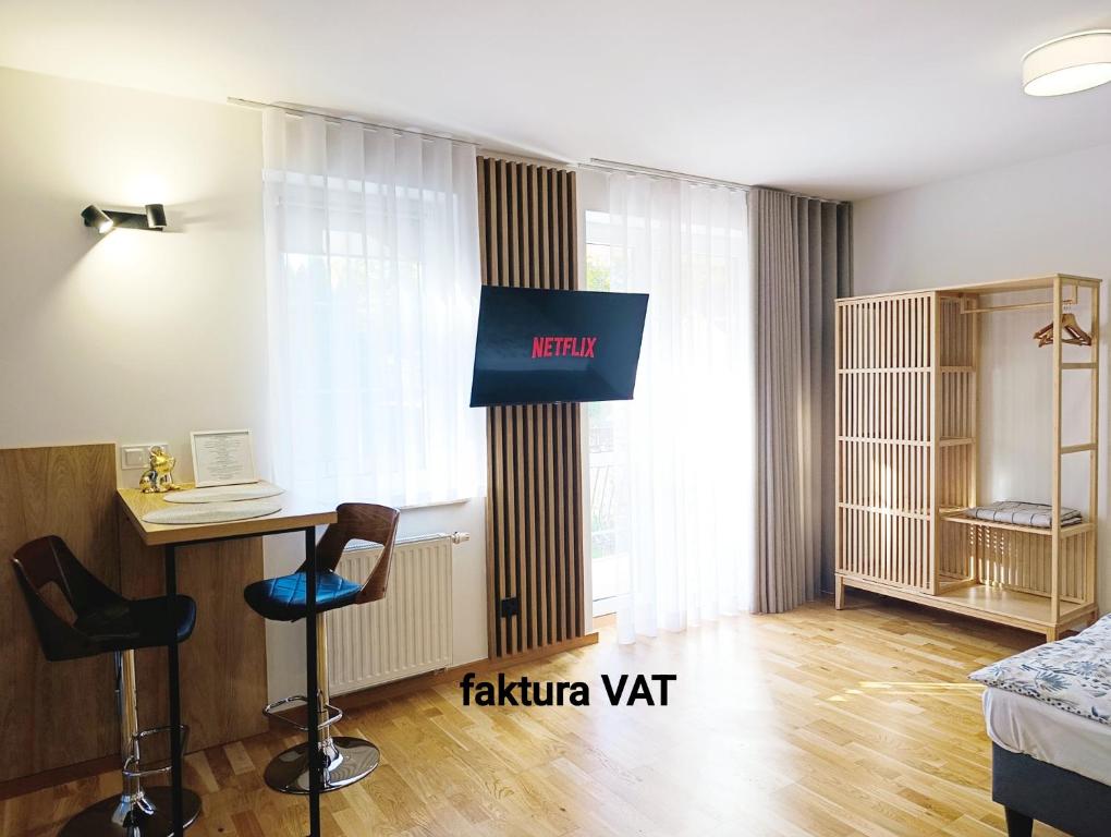 オルシュティンにあるKolory Warmii Apartamenty Biały i Szaryのテレビ、デスク、ベッドが備わる客室です。