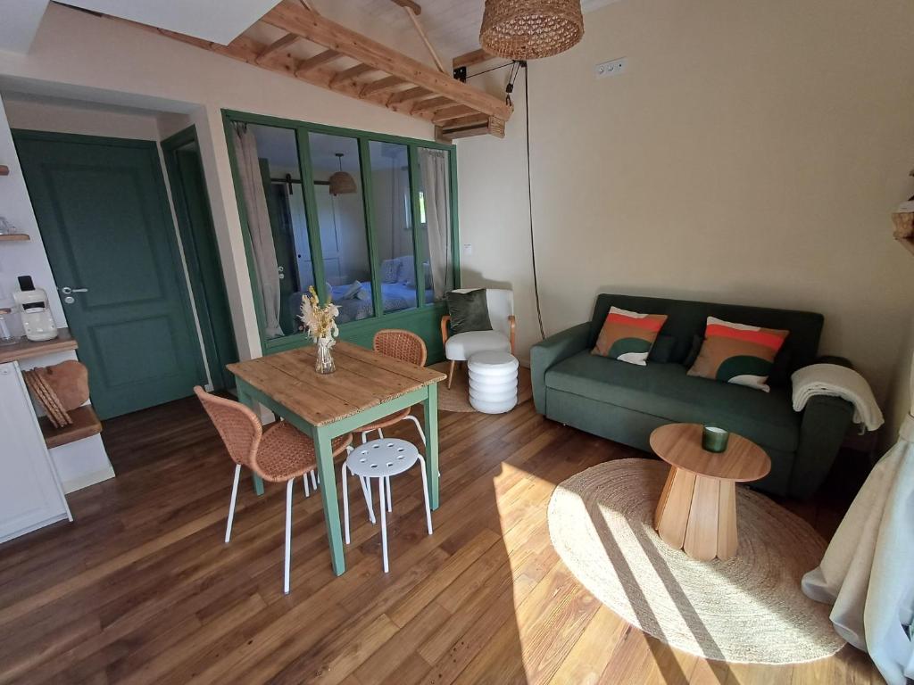 a living room with a green couch and a table at Douce Parenthèse au bord de l'eau in La Celle-sous-Gouzon