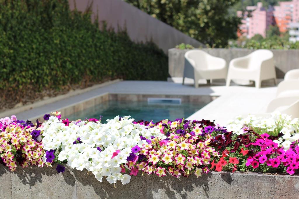 a bunch of flowers in a planter next to a pool at ma-la studios Guimarães in Guimarães