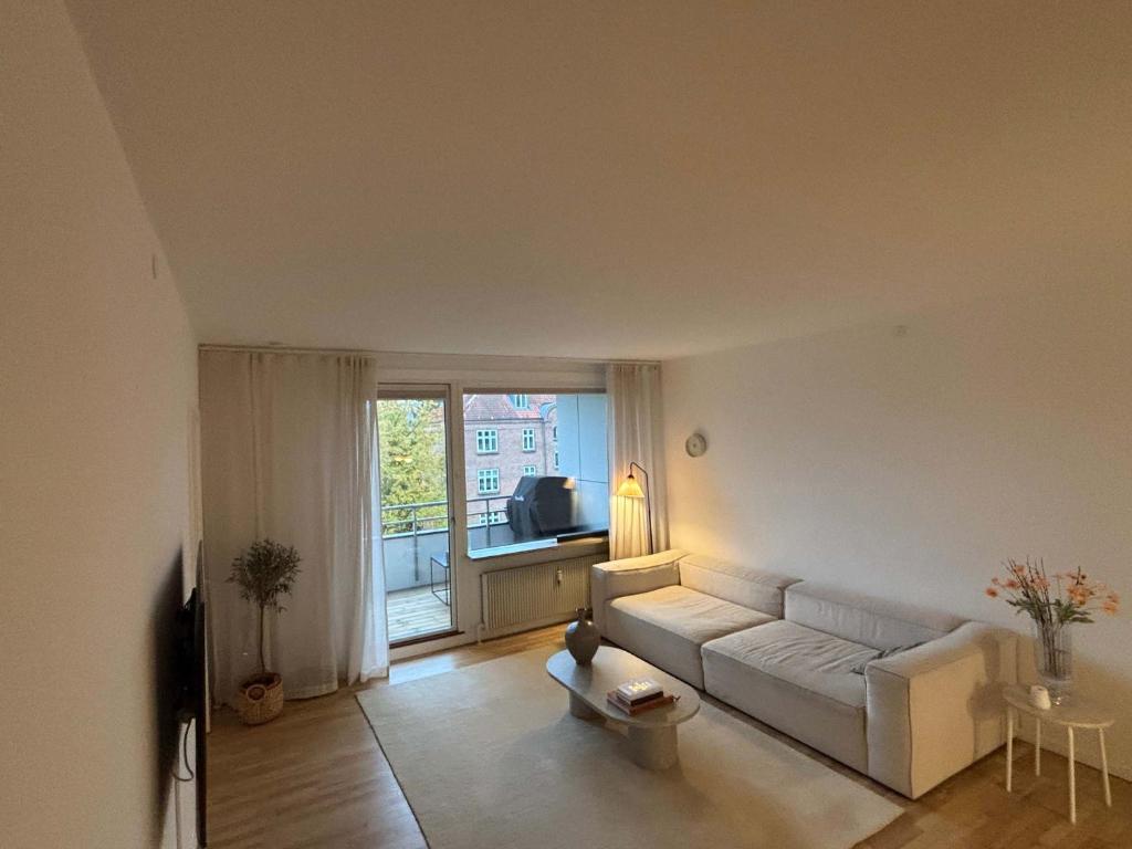 a living room with a white couch and a window at Family apt 10 Minutes From Central in Kongens Lyngby