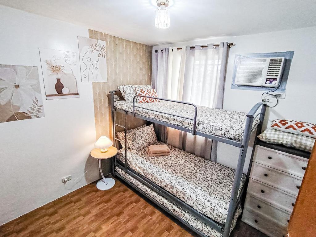 een slaapkamer met 2 stapelbedden en een dressoir bij Cozy Three-Bedroom Staycation House with Netflix, Wi-Fi, and Free Parking Garage near SM Caloocan in Manilla