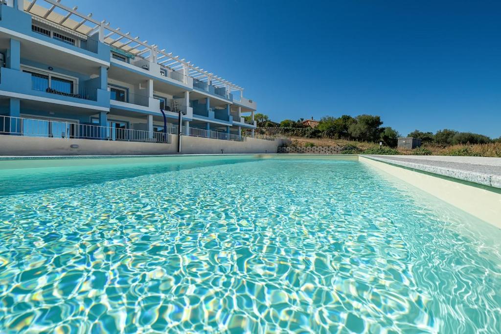 a swimming pool in front of a building at AffittaSardegna - Bilo Elicriso in Trinità dʼAgultu