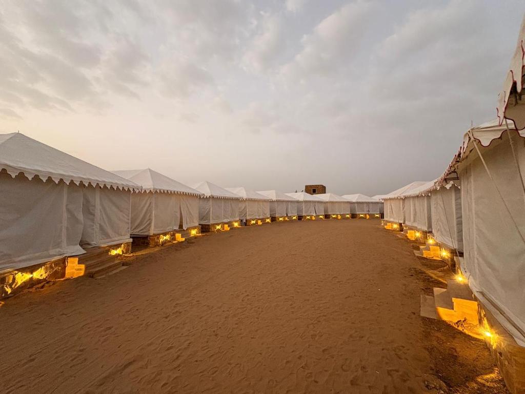 a row of tents on a beach with lights at kalp desert camp in Jaisalmer