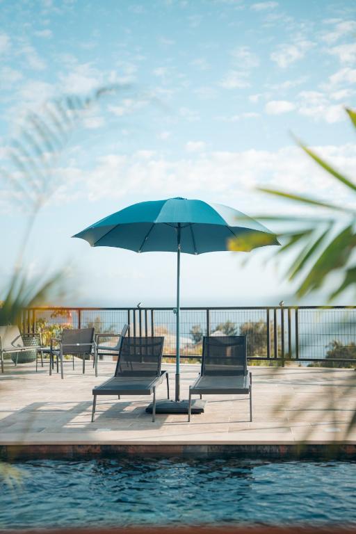 a group of chairs and an umbrella next to a pool at Les Ti Kaz d'Auguste in Les Avirons