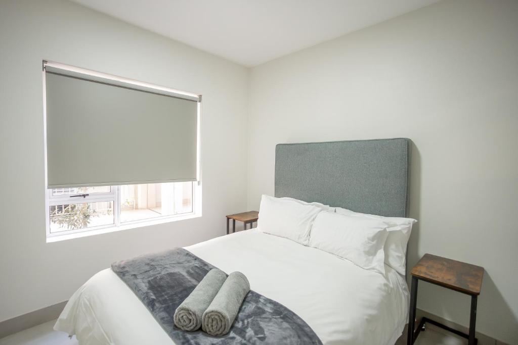 a white bedroom with a bed with a window at Apartment 35 - 1 On York in George
