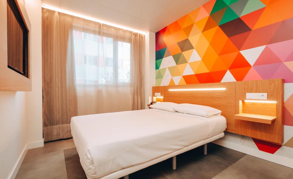 a bedroom with a bed and a colorful wall at Vértice Roomspace in Madrid