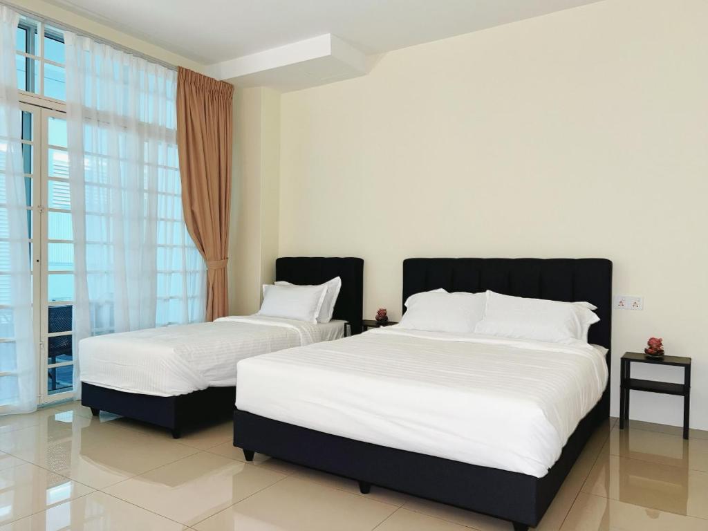 a bedroom with two beds with white sheets and a window at Cozy Private Room for Relaxing Stays in Nibung Tebal