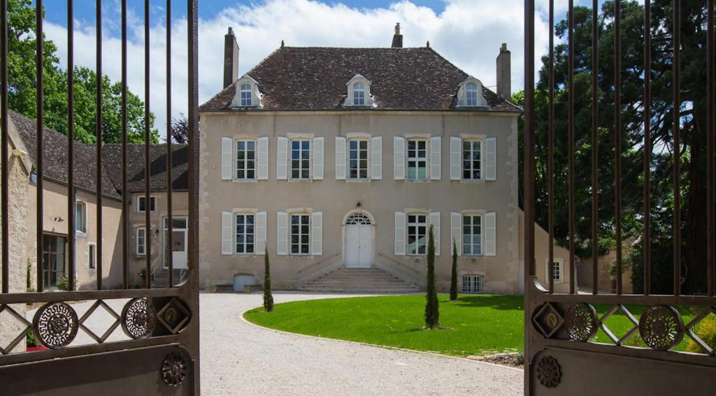 an open gate to a large house with a yard at Chambres d'hôtes Le Clos des Tilleuls in Demigny