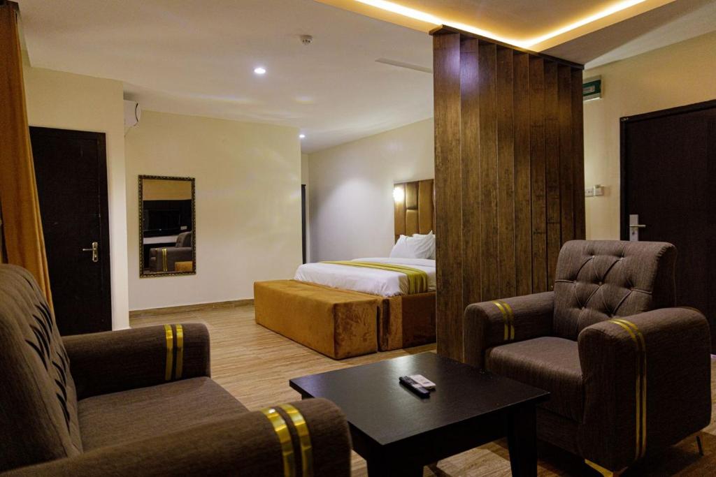 a hotel room with a bed and two chairs and a table at Vizit Hotel & Suites in Benin City