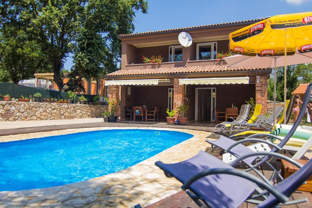 a house with a swimming pool with chairs and an umbrella at Villa Novkovic in Žgaljić