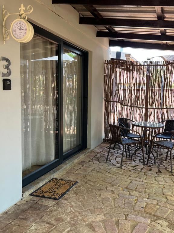 Un patio con una mesa y sillas y un reloj. en 7 At Brainline, en Pretoria