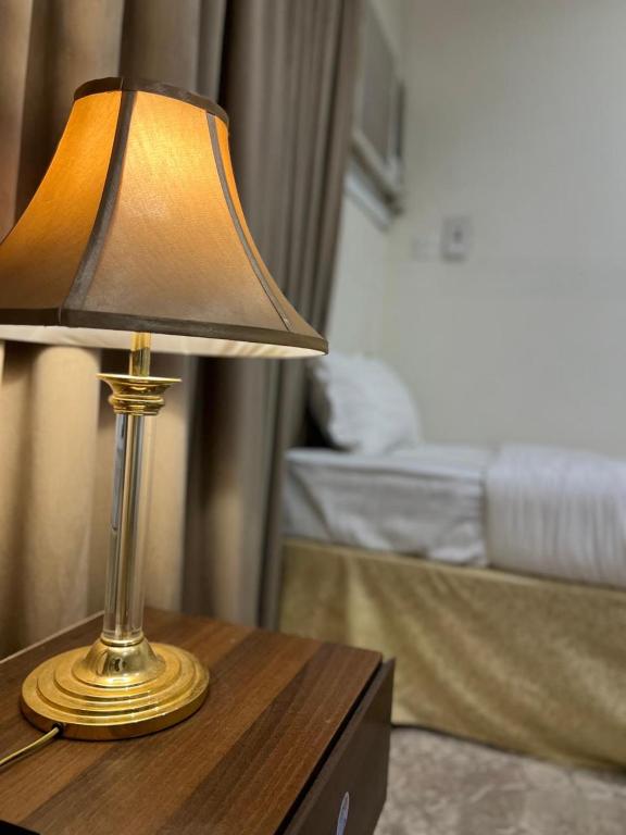 Una lámpara de oro colocada sobre una mesa junto a una cama. en marya appartment, en Medina