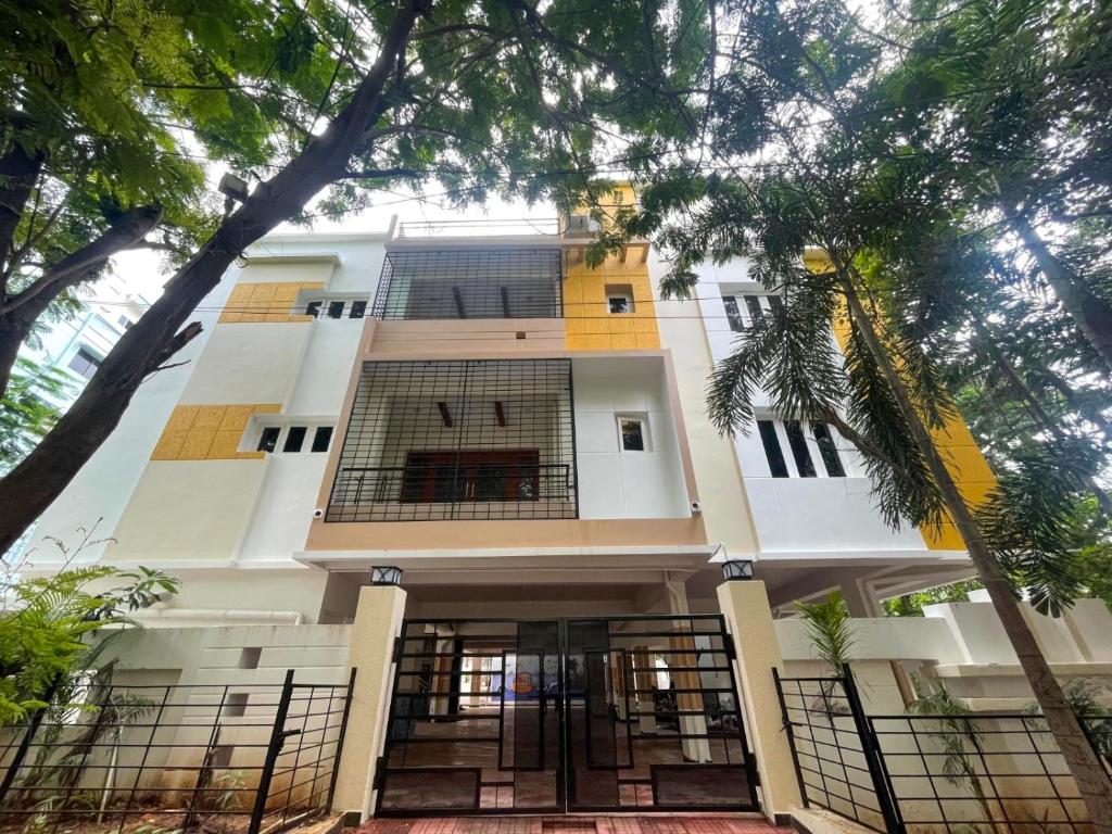 Un gran edificio blanco con árboles delante. en Arrow Service Appartment, en Gachibowli