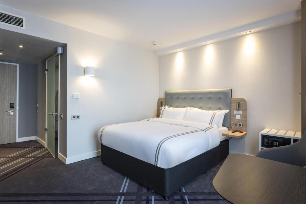 a bedroom with a large white bed and a chair at Premier Inn Freiburg City Süd in Freiburg im Breisgau