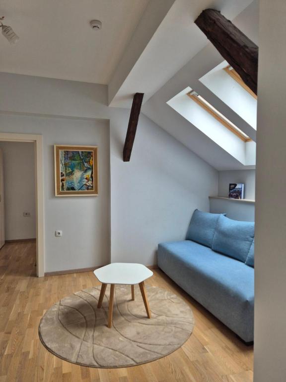 a living room with a blue couch and a table at City Nest Apartments NS in Novi Sad