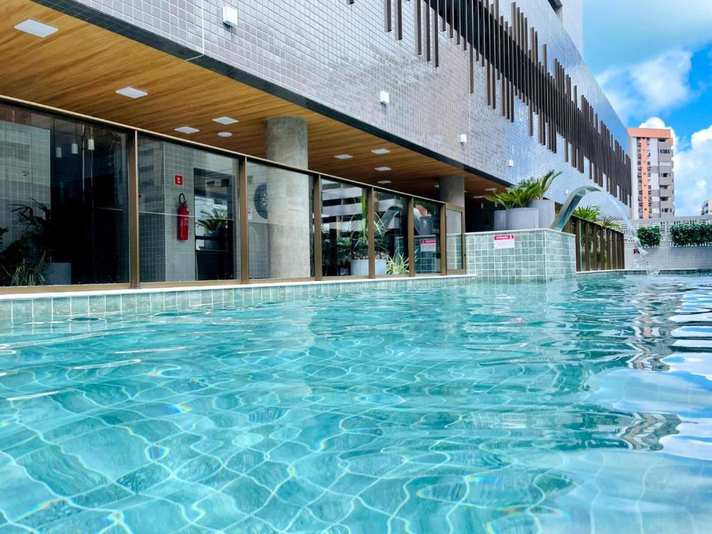 a large swimming pool in front of a building at Studio Design Mar in Maceió