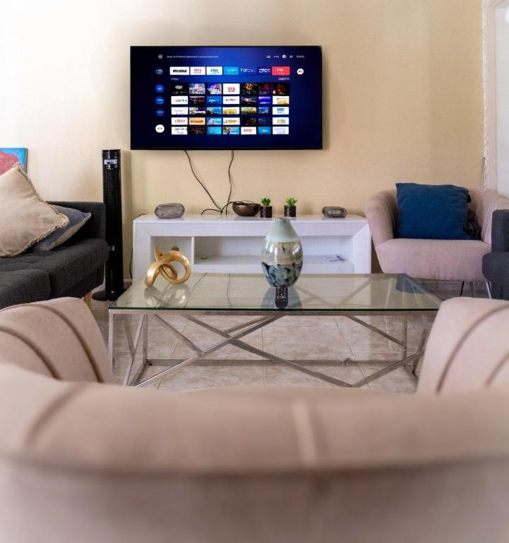 a living room with a glass coffee table and a tv at The Three Sisters Villa in Puerto Plata