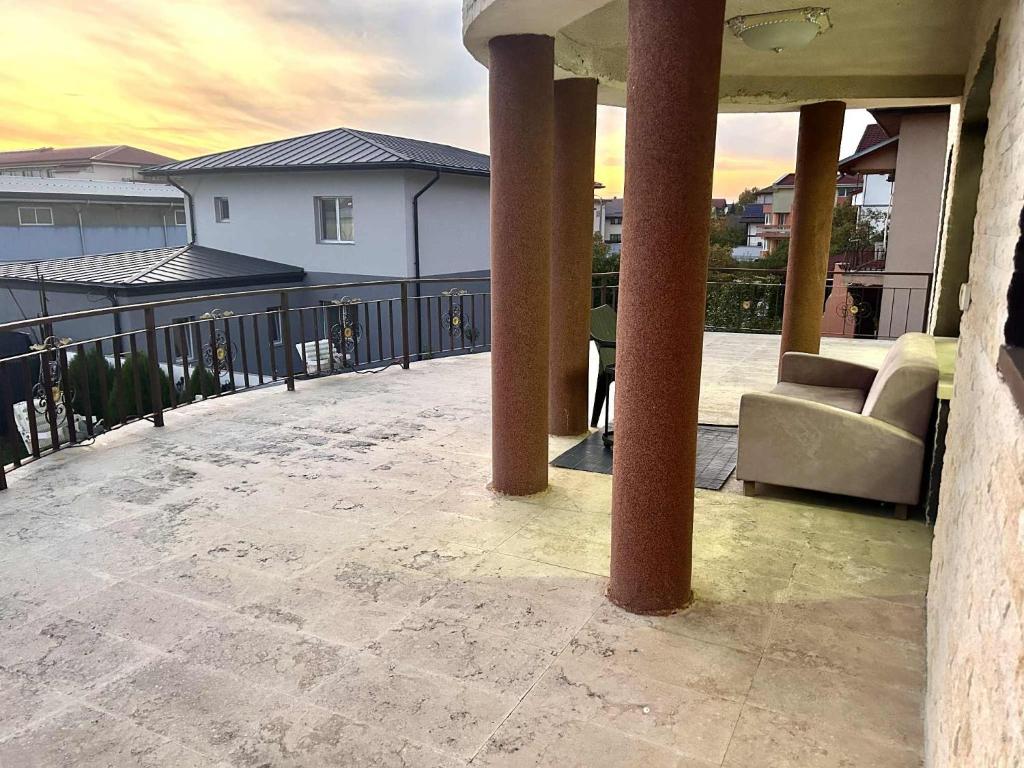 a patio with a couch and chairs on a balcony at Apartament cu Terasă și Vedere la Apus in Voluntari