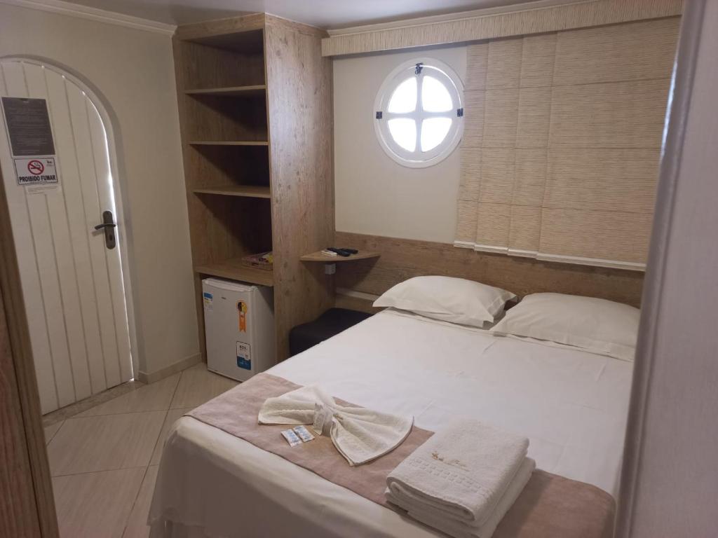 a bedroom with a white bed with a window at Pousada Dom Quixote in São João da Barra
