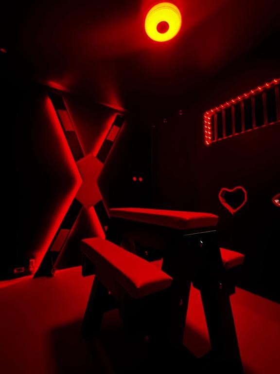 a dark room with a bench and a red light at Love Room Les secrets interdits in Wattignies