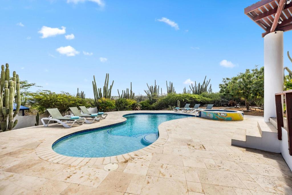 a swimming pool in a yard with chairs and cactus at Beautiful 5BR Villa *Zen*Nature*Views*BBQ*BathTub* in Noord