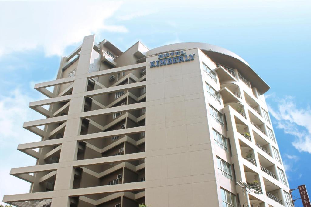 a tall white building with a blue sign on it at Hotel Kimberly Manila in Manila