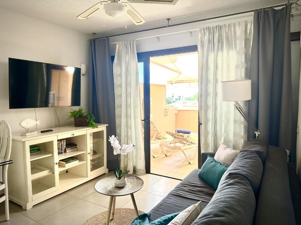 a living room with a blue couch and a television at Royal Garden Sea Views by Deihu Experiences in Playa de las Americas