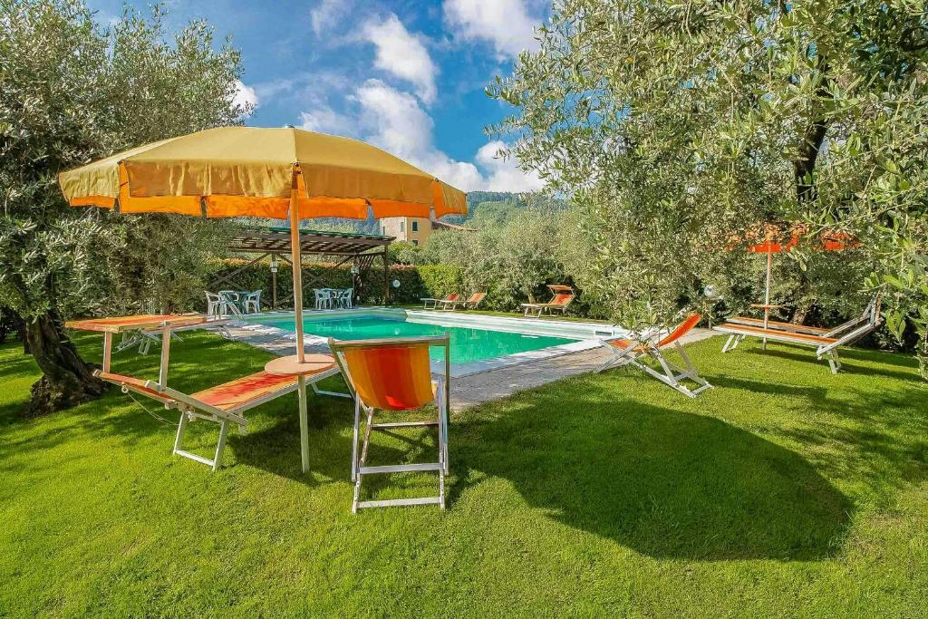 a pool with a table and an umbrella and chairs at Historic Apartment With Swimming Pool Near Lucca in Colle di Compito