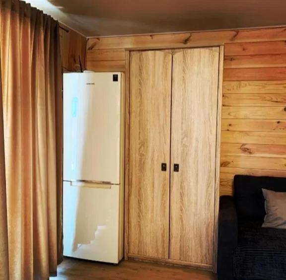 a kitchen with a white refrigerator and wooden walls at Таунхаус in Košice