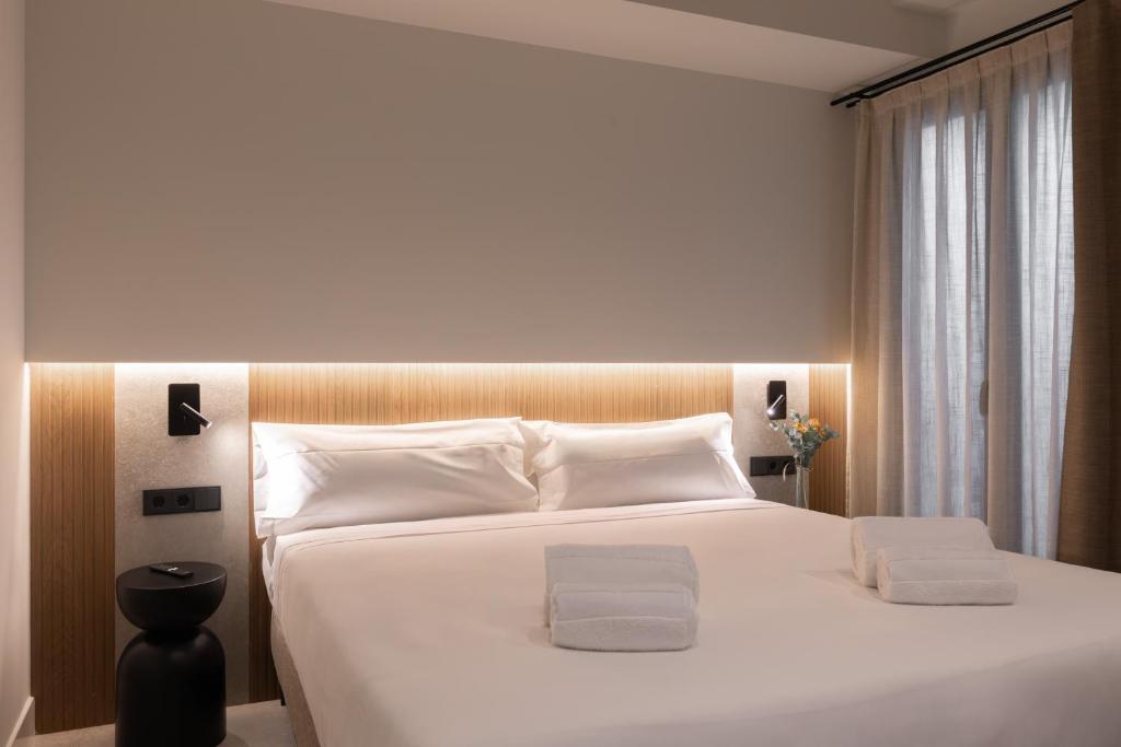 Un dormitorio con una gran cama blanca con almohadas blancas. en Moontels Colón, en Valencia