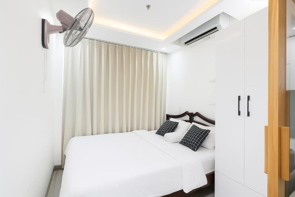 a bedroom with a white bed and a ceiling fan at Louis Luxury Apartment & Hotel in Da Nang