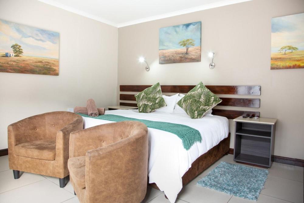 een slaapkamer met een bed en een stoel bij Pinto City Motel East London in East London