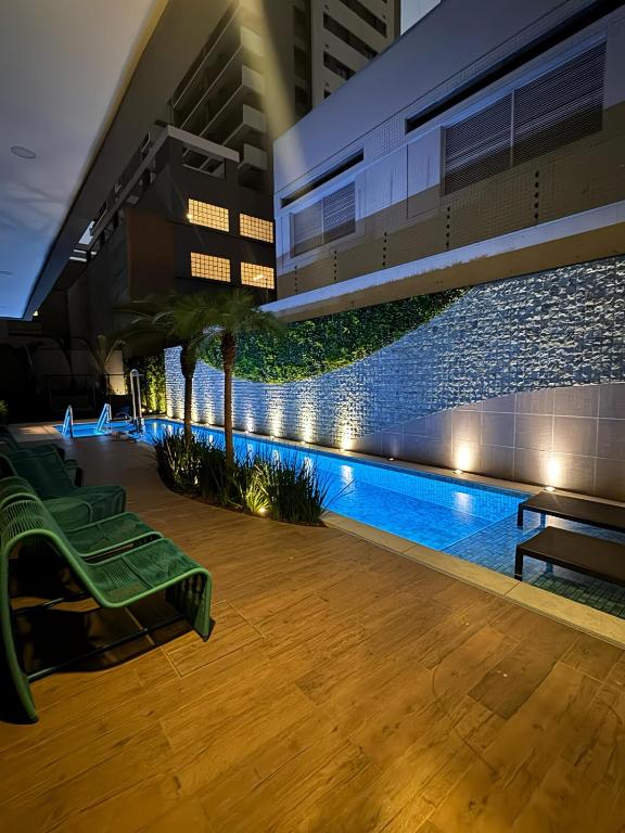 a pool in the middle of a building with a green bench at Apartamento 300 m do metrô Tatuapé in São Paulo