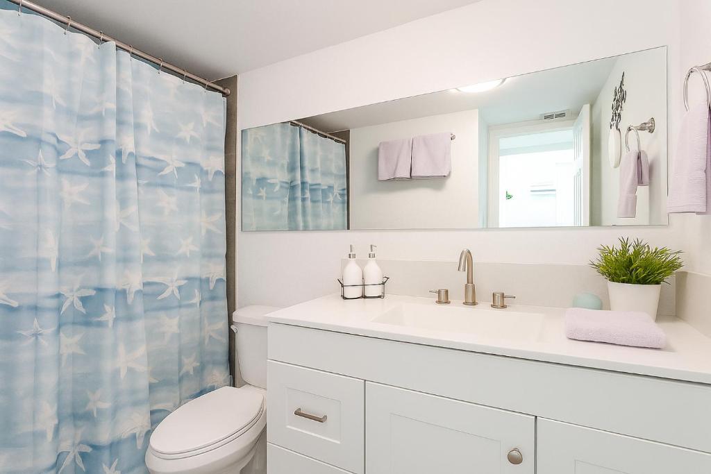 a white bathroom with a sink and a toilet at Oasis Waterfront Treasure Island Apartment with Patio Dock and Johns Pass in St Pete Beach