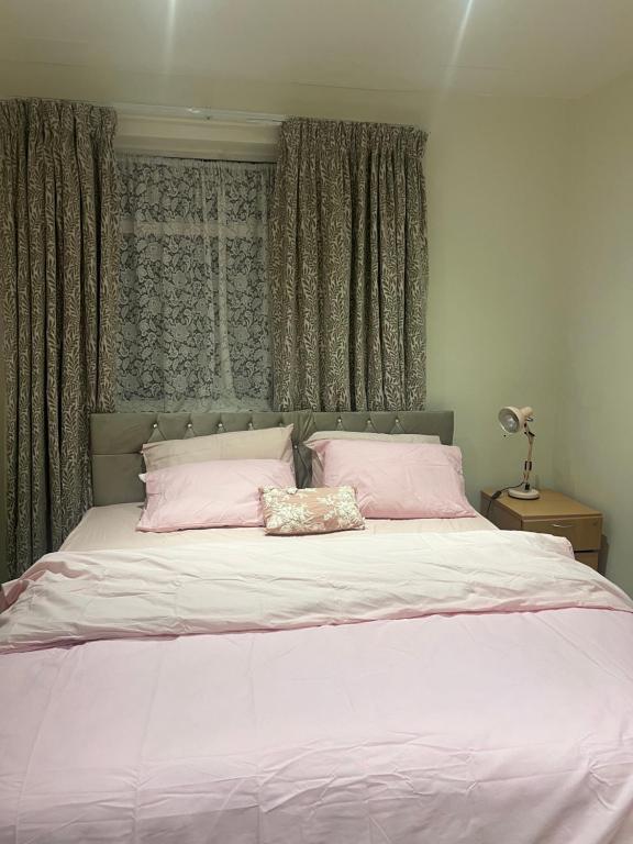 a bedroom with a large bed with pink pillows at Bittern Lodge Homestay with Free Offsite Parking Spacious Kitchen with a Modern Bathroom Near the River Itchen in a peaceful neighborhood in Southampton