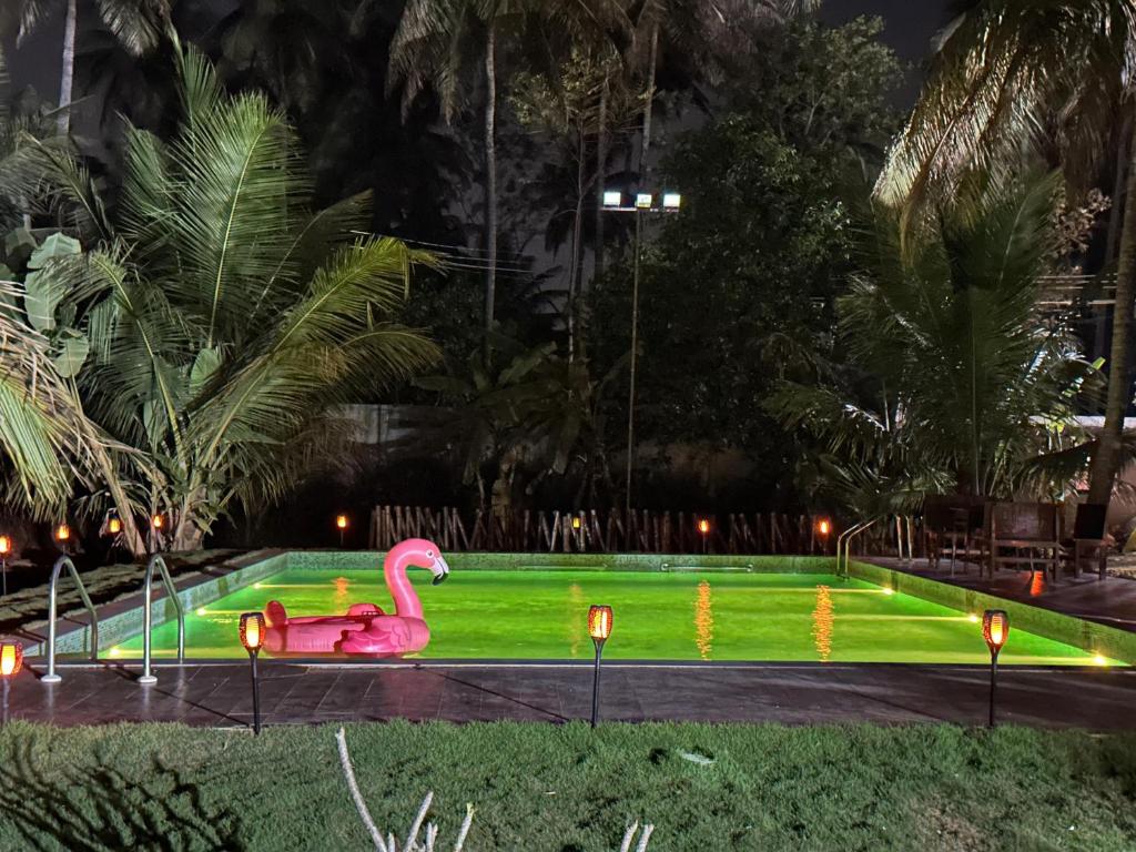a fake pink flamingo in a park at night at Tranquil Farmstay by Vanaja Farms in Rāmanagaram