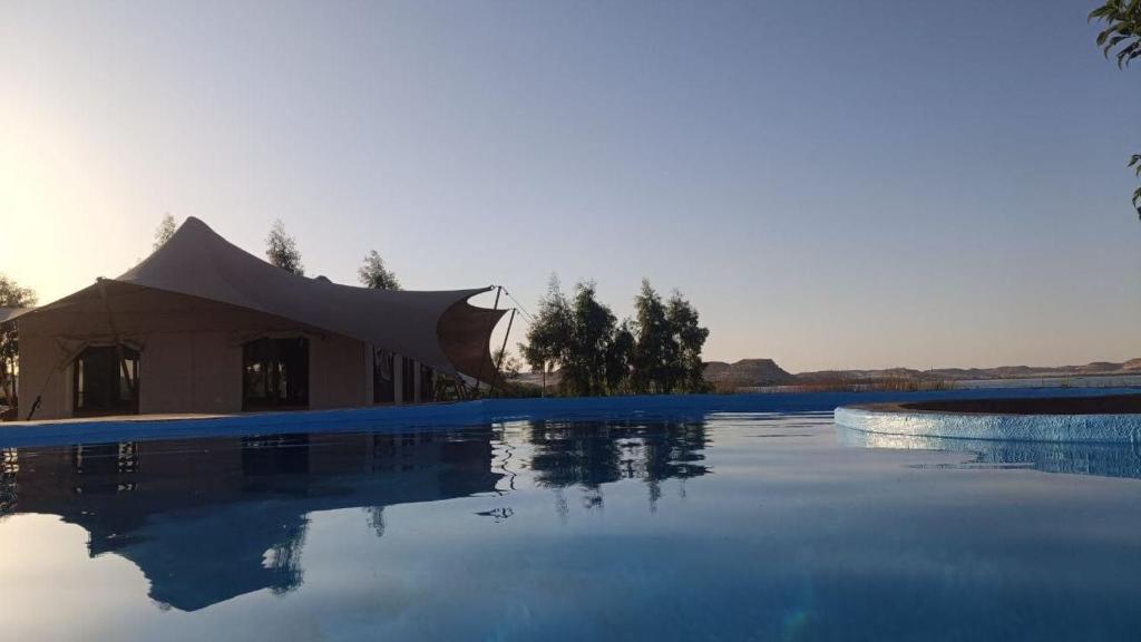 a large swimming pool with a tent in the background at moon retreat in ‘Izbat Mushandid al Kabīrah